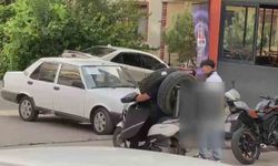 Otomobil lastiğini boynuna asan kuryenin ilginç taşıma yöntemi kameraya yansıdı