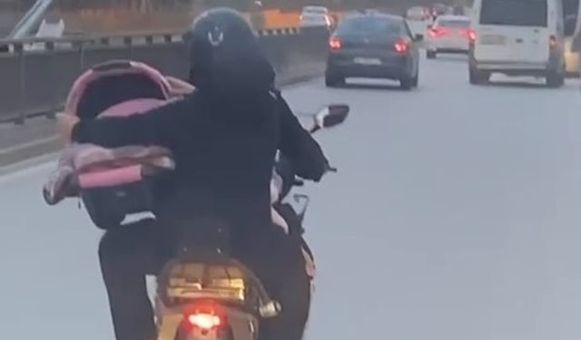 Motosiklet üzerinde bebeği pusetiyle taşıdı